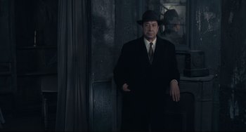 Movie still from “Army of Shadows” (1969), directed by Jean-Pierre Melville – A man in a suit and hat leaning against a wall; Medium shot, Low angle