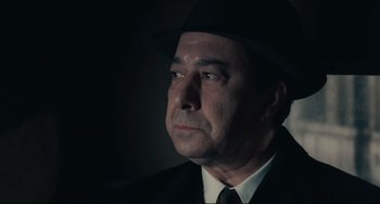 Movie still from “Army of Shadows” (1969), directed by Jean-Pierre Melville – A man in a suit and a hat is in the dark; Close Up shot, Low angle