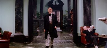 Movie still from “Around the World in 80 Days” (1956), directed by John Farrow – A man in a suit and tie standing in front of a doorway; Wide shot, Low angle