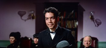 Movie still from “Around the World in 80 Days” (1956), directed by John Farrow – A man wearing a suit and bow tie in front of a book case; Close Up shot, Low angle