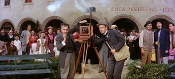 Movie still from “Around the World in 80 Days” (1956), directed by John Farrow – Two men are standing next to an old fashioned camera; Medium shot, Low angle