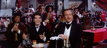 Movie still from “Around the World in 80 Days” (1956), directed by John Farrow – A group of men sitting at a table in front of a crowd; Medium shot, Low angle