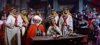 Movie still from “Around the World in 80 Days” (1956), directed by John Farrow – A group of men standing in front of a wooden table; Wide shot, Over the shoulder angle