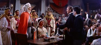 Movie still from “Around the World in 80 Days” (1956), directed by John Farrow – A group of men standing next to each other at a table; Medium shot, Over the shoulder angle