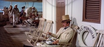 Movie still from “Around the World in 80 Days” (1956), directed by John Farrow – A man sitting in a rocking chair wearing a straw hat; Wide shot, High angle