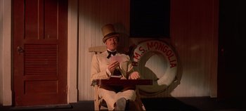Movie still from “Around the World in 80 Days” (1956), directed by John Farrow – A man sitting in a chair holding a deck of playing cards; Medium shot, High angle