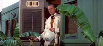 Movie still from “Around the World in 80 Days” (1956), directed by John Farrow – A man in a white suit and a white hat standing in front of a door; Medium shot, Low angle