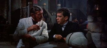 Movie still from “Around the World in 80 Days” (1956), directed by John Farrow – Two men sitting at a table talking to each other; Medium shot, Over the shoulder angle