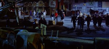 Movie still from “Around the World in 80 Days” (1956), directed by John Farrow – A group of people walking down a street at night; Extreme Wide shot, High angle