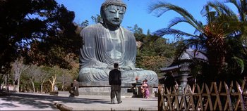 Movie still from “Around the World in 80 Days” (1956), directed by John Farrow – A man standing in front of a large buddha statue; Extreme Wide shot, Low angle