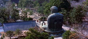 Movie still from “Around the World in 80 Days” (1956), directed by John Farrow – A large statue of a buddha sits in the middle of a park; Extreme Wide shot, High angle