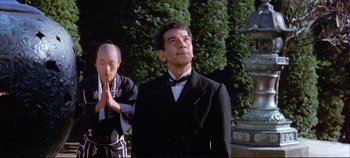 Movie still from “Around the World in 80 Days” (1956), directed by John Farrow – A man in a suit and bow tie standing next to another man in a suit and bow tie; Medium shot, Low angle