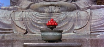 Movie still from “Around the World in 80 Days” (1956), directed by John Farrow – A bowl of tomatoes in front of a statue of buddha; Wide shot, High angle