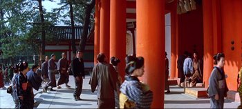 Movie still from “Around the World in 80 Days” (1956), directed by John Farrow – A group of people standing around a red building; Extreme Wide shot, Low angle