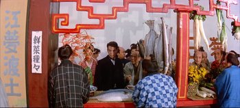 Movie still from “Around the World in 80 Days” (1956), directed by John Farrow – A group of people standing in front of a table with fish; Medium shot, High angle