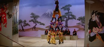 Movie still from “Around the World in 80 Days” (1956), directed by John Farrow – A group of people standing on top of each other in front of trees; Extreme Wide shot, Low angle