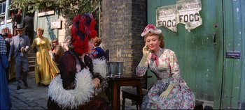 Movie still from “Around the World in 80 Days” (1956), directed by John Farrow – Two women dressed in period costumes sitting at a table; Medium shot, Over the shoulder angle