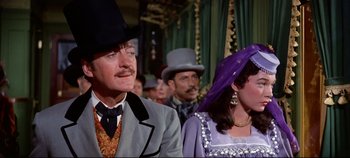Movie still from “Around the World in 80 Days” (1956), directed by John Farrow – A man and a woman wearing hats in front of a crowd; Medium shot, Over the shoulder angle