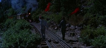 Movie still from “Around the World in 80 Days” (1956), directed by John Farrow – Two men are standing on a train track waving flags; Wide shot, High angle