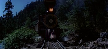 Movie still from “Around the World in 80 Days” (1956), directed by John Farrow – A steam train traveling down the tracks near a forest; Extreme Wide shot, Low angle