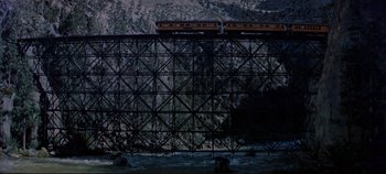 Movie still from “Around the World in 80 Days” (1956), directed by John Farrow – A train on a bridge over a body of water; Extreme Wide shot, Low angle
