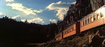 Movie still from “Around the World in 80 Days” (1956), directed by John Farrow – A train traveling down tracks next to a mountain side; Extreme Wide shot, Low angle