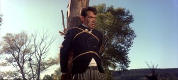 Movie still from “Around the World in 80 Days” (1956), directed by John Farrow – A man in a suit tied to a tree trunk; Medium shot, Low angle