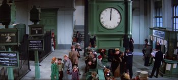 Movie still from “Around the World in 80 Days” (1956), directed by John Farrow – A group of people standing around a large clock; Wide shot, High angle