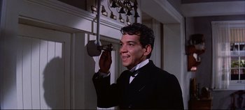 Movie still from “Around the World in 80 Days” (1956), directed by John Farrow – A man in a suit and bow tie holding a microphone; Medium shot, Low angle