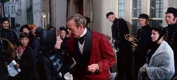 Movie still from “Around the World in 80 Days” (1956), directed by John Farrow – A man in a red jacket talking to a woman in a black suit; Medium shot, Over the shoulder angle