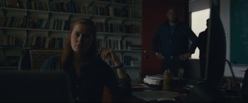 Movie still from “Arrival” (2016), directed by Denis Villeneuve – A woman sitting at a desk in front of a man; Medium shot, Over the shoulder angle