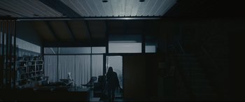 Movie still from “Arrival” (2016), directed by Denis Villeneuve – A person standing in a room with a chair and a window; Wide shot, Low angle
