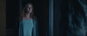 Movie still from “Arrival” (2016), directed by Denis Villeneuve – A woman standing next to a window in a dark room; Medium shot, Low angle