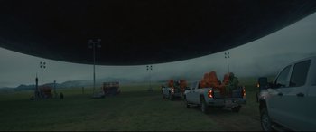 Movie still from “Arrival” (2016), directed by Denis Villeneuve – A group of trucks parked in a field under a dark sky; Extreme Wide shot, Low angle