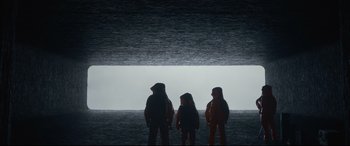 Movie still from “Arrival” (2016), directed by Denis Villeneuve – Three people are standing in front of the water at night; Wide shot, Low angle
