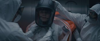 Movie still from “Arrival” (2016), directed by Denis Villeneuve – A person wearing a motorcycle helmet in a room; Medium shot, Over the shoulder angle