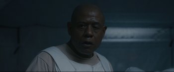 Movie still from “Arrival” (2016), directed by Denis Villeneuve – A man with a bald head is looking at the camera; Close Up shot, Over the shoulder angle