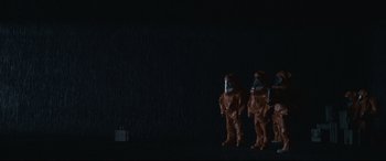 Movie still from “Arrival” (2016), directed by Denis Villeneuve – A couple of toy figurines standing next to each other on the ground; Wide shot, Low angle