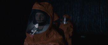 Movie still from “Arrival” (2016), directed by Denis Villeneuve – A man in an orange suit and a helmet; Medium shot, Over the shoulder angle