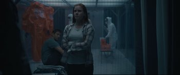 Movie still from “Arrival” (2016), directed by Denis Villeneuve – A woman standing with her arms crossed in a room; Medium shot, Over the shoulder angle