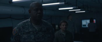 Movie still from “Arrival” (2016), directed by Denis Villeneuve – A man in a military fatigues standing next to another man in fatigues; Medium shot, Low angle