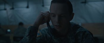 Movie still from “Arrival” (2016), directed by Denis Villeneuve – A man in military fatigues talking on a cell phone; Close Up shot, High angle