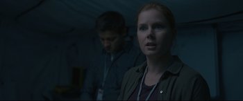 Movie still from “Arrival” (2016), directed by Denis Villeneuve – A woman standing next to a man in a dark room; Close Up shot, Over the shoulder angle