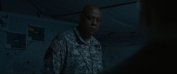 Movie still from “Arrival” (2016), directed by Denis Villeneuve – A man in military fatigues standing in a tent; Medium shot, Low angle