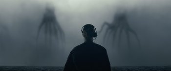 Movie still from “Arrival” (2016), directed by Denis Villeneuve – A person wearing headphones looking out to sea; Medium shot, Over the shoulder angle
