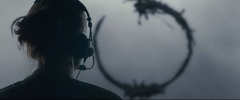 Movie still from “Arrival” (2016), directed by Denis Villeneuve – A person wearing a headset and looking out a plane window; Close Up shot, Over the shoulder angle