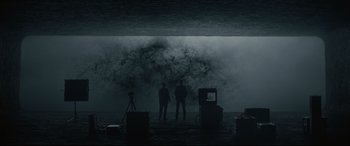 Movie still from “Arrival” (2016), directed by Denis Villeneuve – Two people standing in front of a wave in a dark room; Extreme Wide shot, Low angle