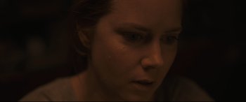 Movie still from “Arrival” (2016), directed by Denis Villeneuve – A woman's face in a dimly - lit room; Close Up shot, Over the shoulder angle