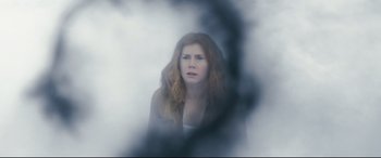 Movie still from “Arrival” (2016), directed by Denis Villeneuve – A red haired woman is looking at the camera through a foggy window; Close Up shot, Low angle