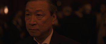 Movie still from “Arrival” (2016), directed by Denis Villeneuve – An older man wearing a suit and bow tie; Close Up shot, Over the shoulder angle